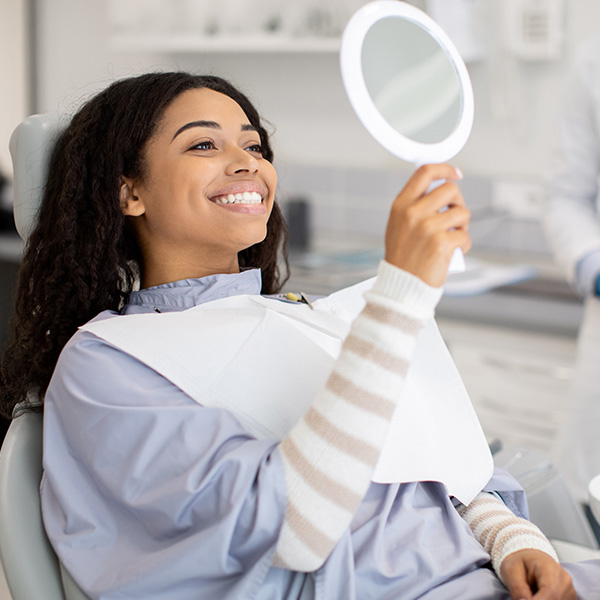girl smiling and looking at her teeth