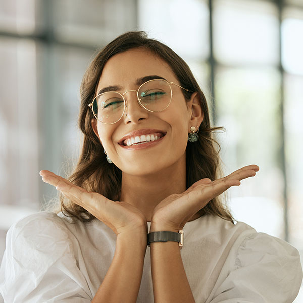 Cheerful business woman with glasses posing with her hands under her face showing her smile